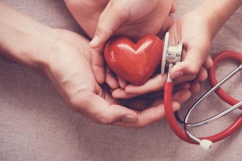 Hands holding a red heart and a stethoscope
